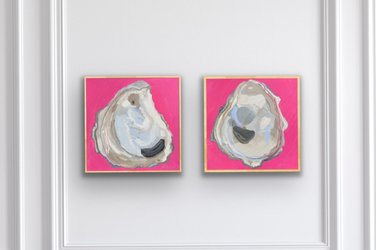 Two pink Charleston oyster paintings by artist Tara Caswell displayed on a white paneled wall.